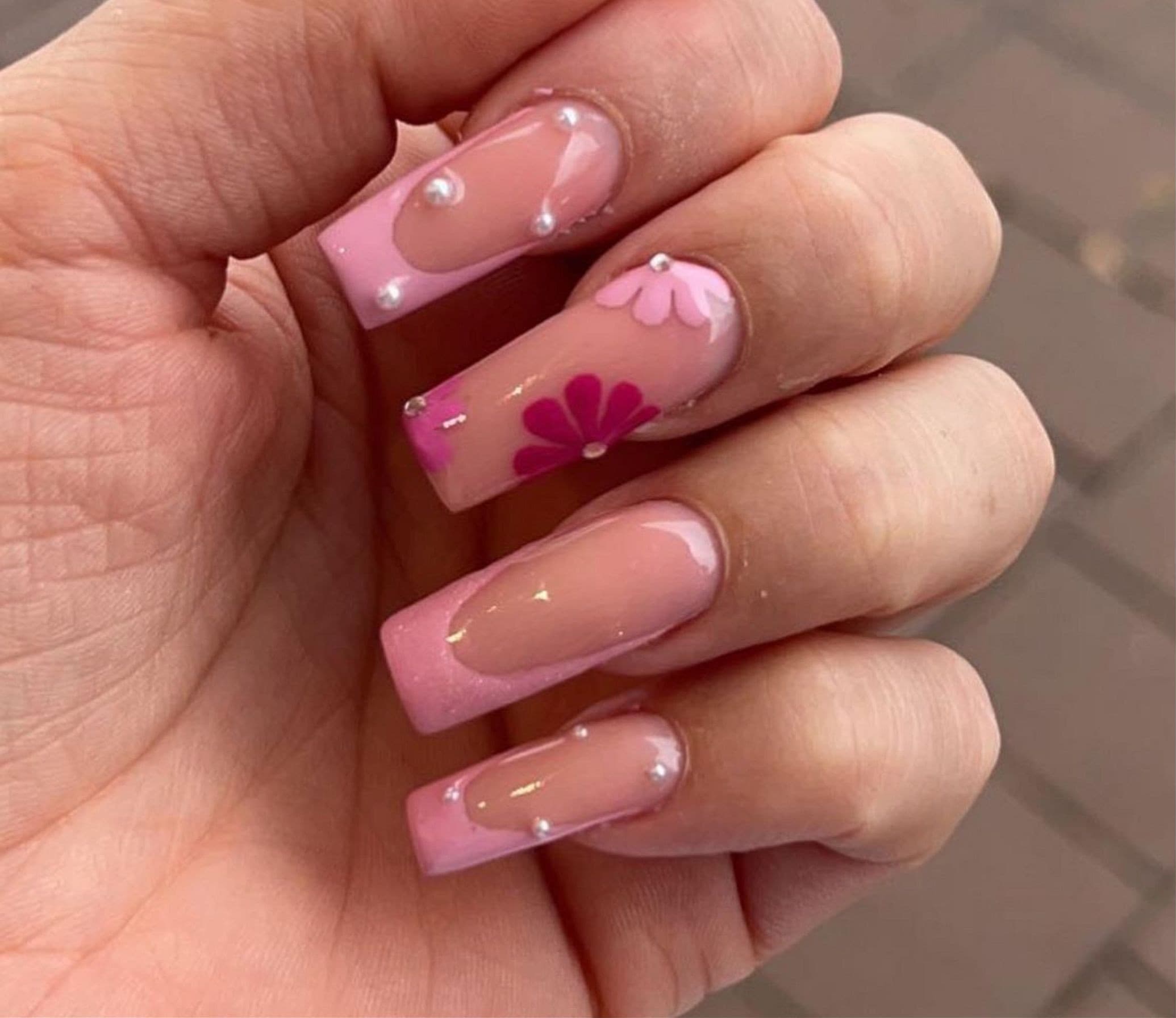 Nägel in Rosé mit pinkfarbener French-Spitze, Blütenmotiv und Perlen
