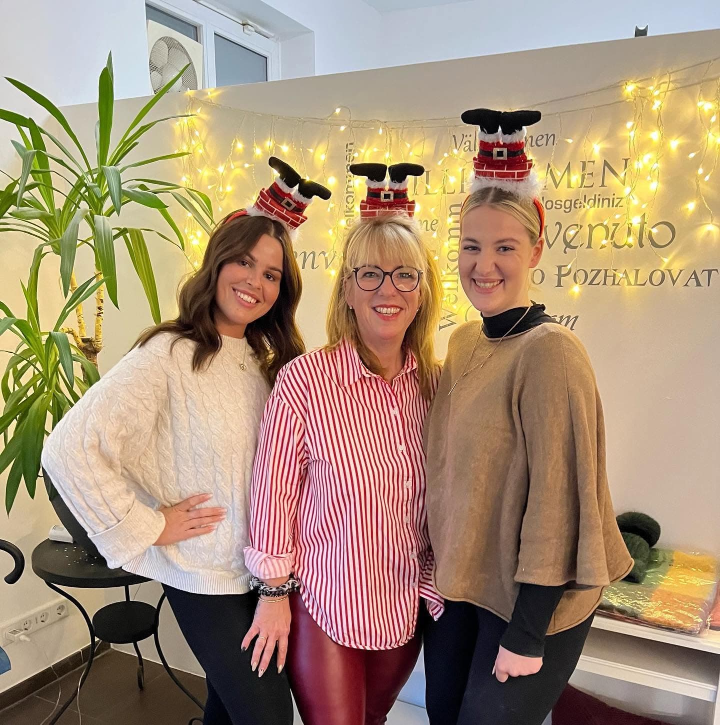 Drei Frauen aus dem Team im Studio vor einer Lichterkette, mit weihnachtlichem Kopfschmuck